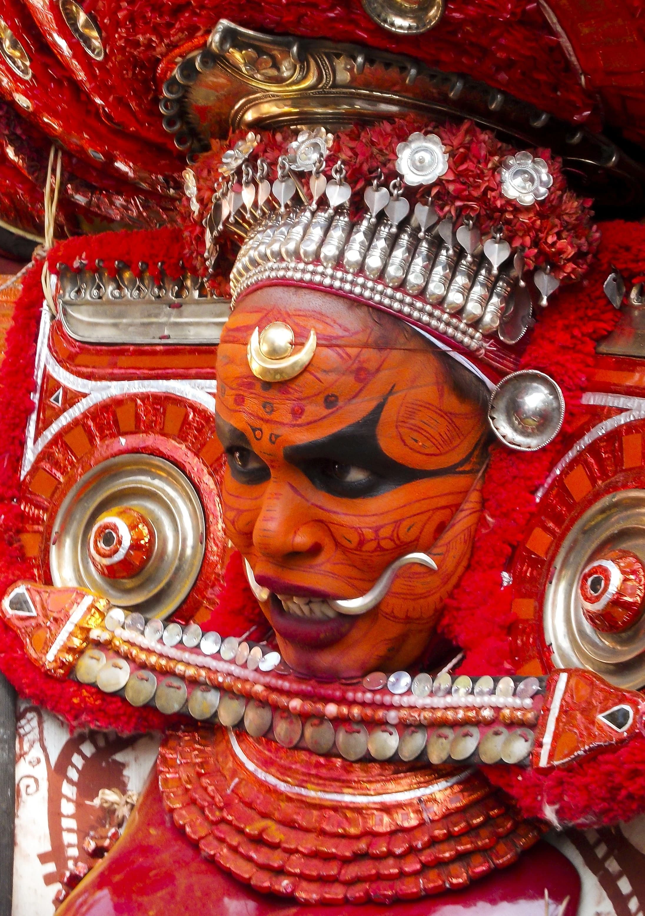 Theyyam performer in vibrant costume during a community festival